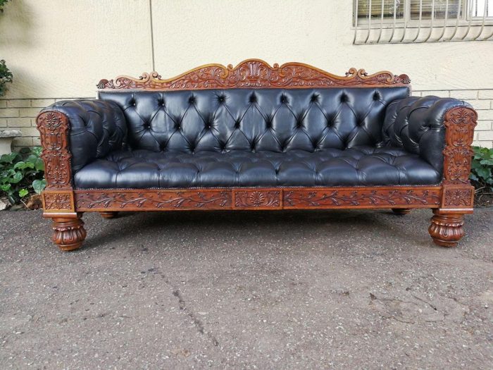 An Anglo Indian Carved Rosewood and Teak settee with brass castors