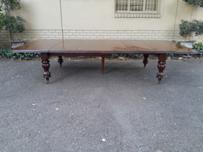 A Massive and Rare Victorian Mahogany Dining / Boardroom Extension table with Four Extensions and Fifth Supporting Leg in the Middle on Original Brass Castors