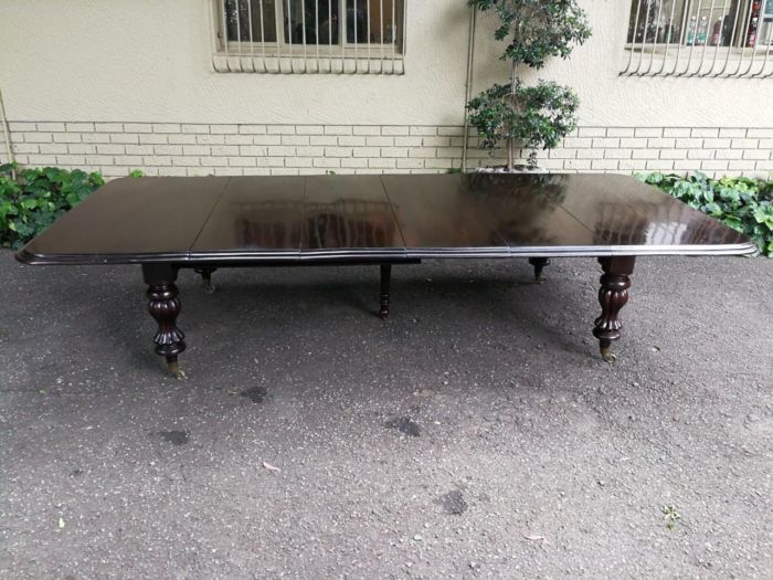 Rare and of large proportion early Victorian mahogany extension dining room/board room table with four extensions and fifth support leg in the middle on original brass castors