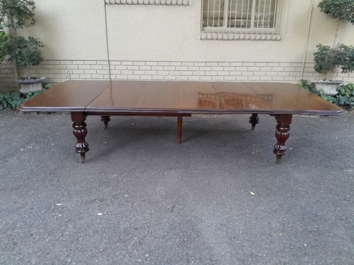 A Massive and Rare Victorian Mahogany Dining / Boardroom Extension table with Four Extensions and Fifth Supporting Leg in the Middle on Original Brass Castors - Image 3