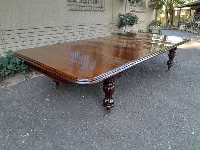 A Massive and Rare Victorian Mahogany Dining / Boardroom Extension table with Four Extensions and Fifth Supporting Leg in the Middle on Original Brass Castors - Image 4