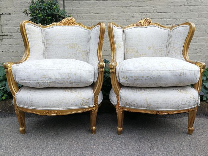 A Pair Of 20th Century French Style Gilt Bergere Armchairs Upholstered In A Custom-Made Hand Printed Linen With Gold Script Design By The Crown Collection