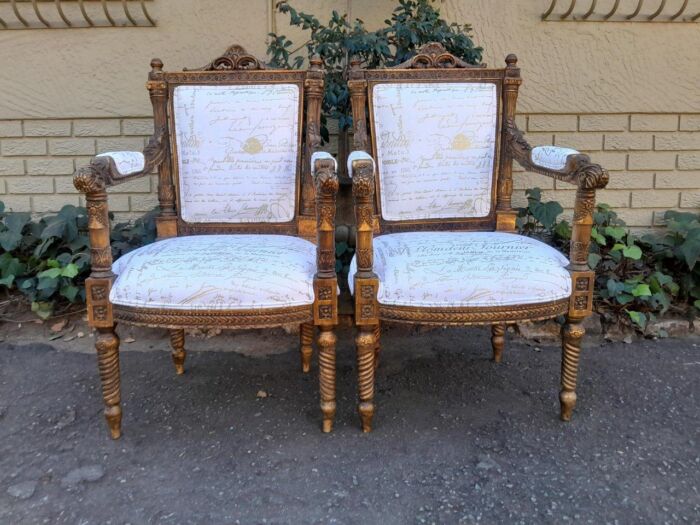 A Pair of 20th Century French Style Carved and Hand Gilded Armchairs Upholstered in a Custom and Handmade Gold Script Linen for The Crown Collection