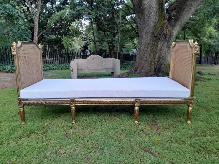 A French Style Hand Gilded Rattan Day Bed Upholstered In A White French Linen With Four Large Size Scatter Cushions