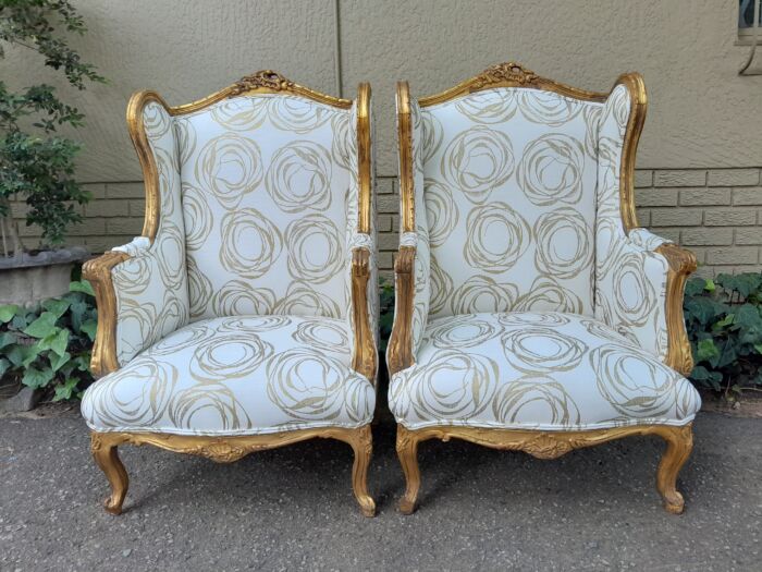 A French Style Pair of Hand Gilded Carved Wingback Chairs Upholstered in a Custom Made for The Crown Collection Cotton / Linen Fabric