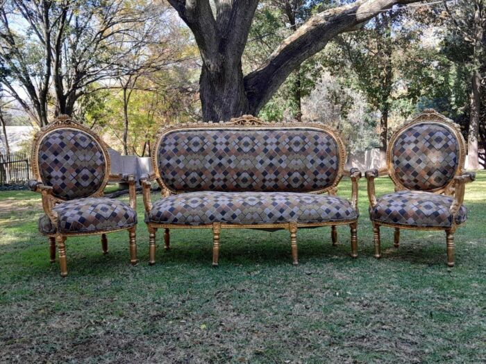 A 20th Century French Ornately Carved Wooden Gilded Set Of Settee And Pair Of Armchairs  Upholstered In A Custom Made Linen For The Crown Collection