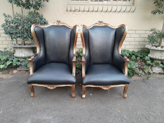 A Pair Of French Style Louis XVI Style Carved And Hand Gilded Wingback Chairs Upholstered In Leather