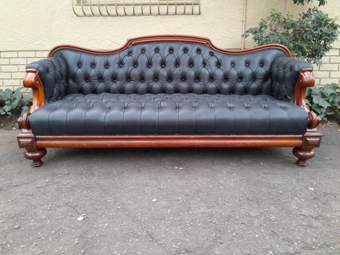 A 19th Century Victorian Circa 1880  Mahogany Ornately Carved Wooden With Brass Castors And Upholstered In Deep  Buttoned Leather