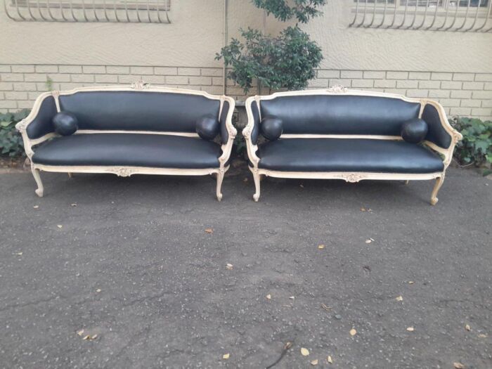 A 20TH Century Pair of French Style Carved Walnut Settees in a Contemporary Bleached Finish and Upholstered in leather with a decorative leather ball