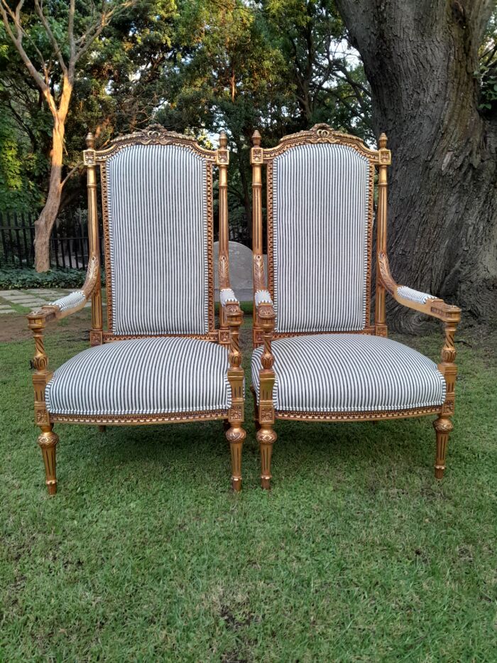 A Pair of French Rococo Style Ornately Carved Giltwood Arm Chairs Upholstered in a Contemporary Ticking Fabric