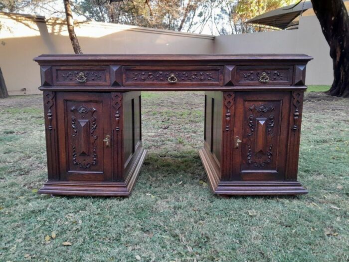 A 20th Century Ornately Carved Oak Pedestal Desk with Drawers