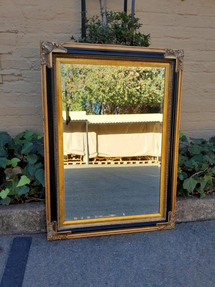 A 20th Century Carved Giltwood And Black Framed Bevelled Mirror