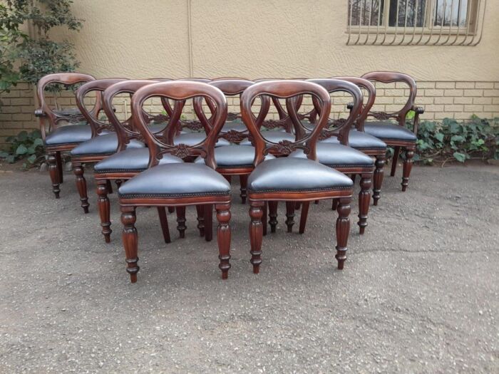 A 20th Century Set of Fourteen (14) Victorian-Style Mahogany Bustle Back and Upholstered in Leather  Comprising of a Pair of Armchairs / Carvers and Twelve Dining Chairs 