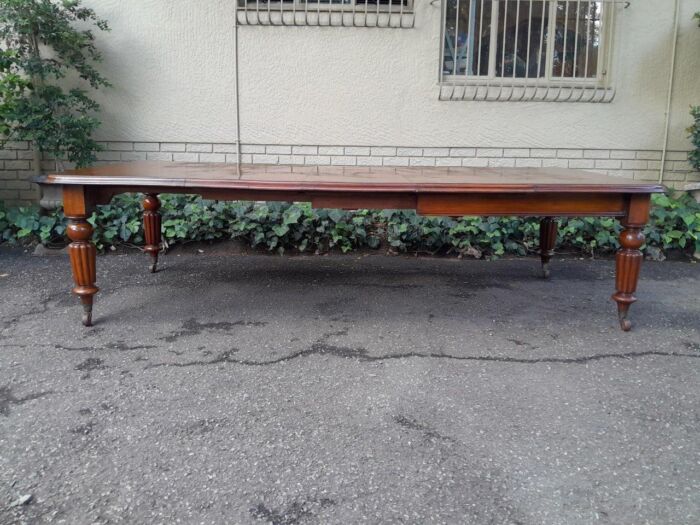 An Antique Edwardian Extending Dining Table with Heavily Carved Legs on Castors and with Crank Handle