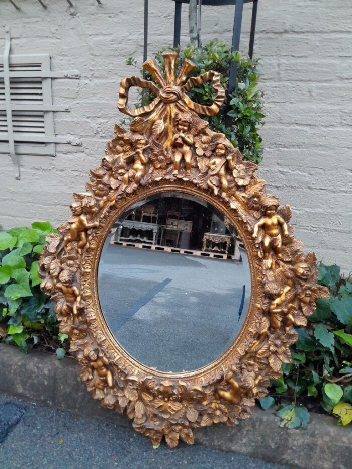 A 20th Century Baroque Style Heavily Carved And Ornate Gilt-Framed Bevelled Glass Mirror