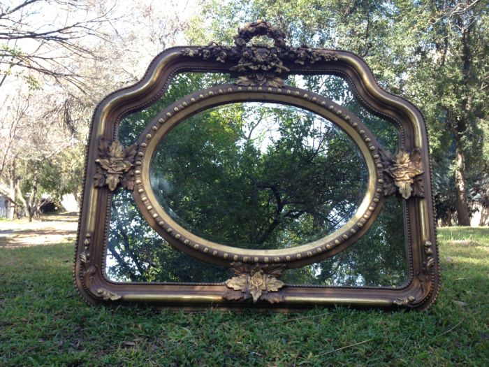 A French Ornate carved mirror with a bevelled oval centre section